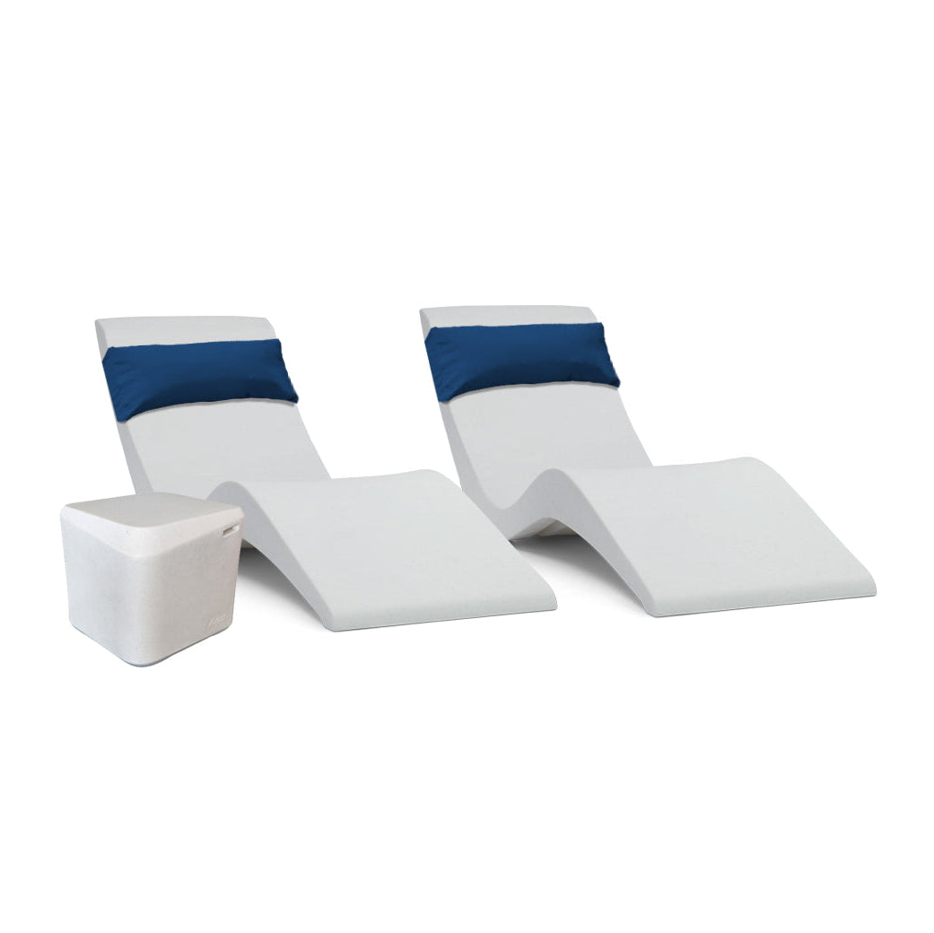 Two sleek white AquaOutdoors Pool Lounge Chairs with blue headrest cushions are set against a plain background, accompanied by a small white side table with a faceted geometric design, perfect for relaxing on the tanning shelf with your Aqua Bundle essentials.