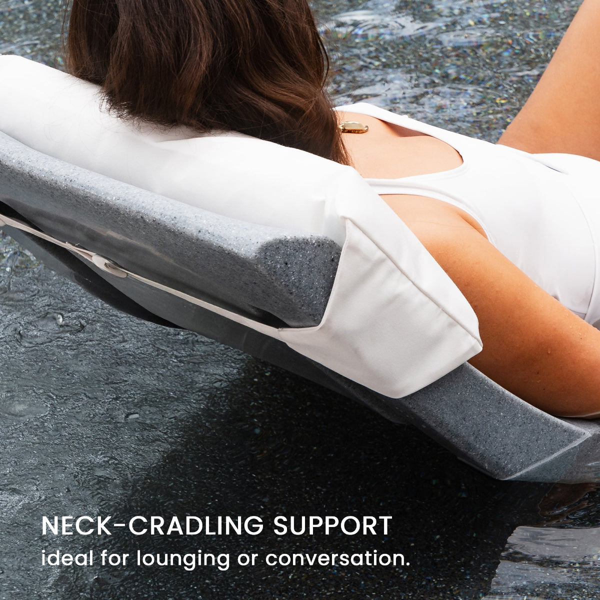 Person lounging in a pool on a floating chair with neck support, wearing a white swimsuit. Text reads, Neck-cradling support ideal for lounging or conversation. Water ripples around the chair.