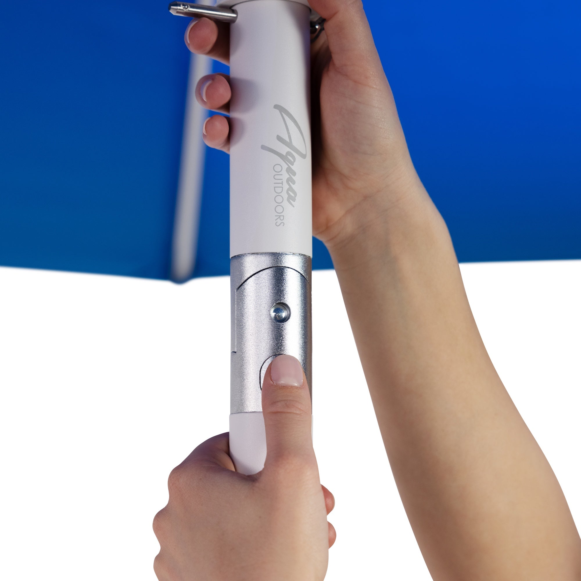 Close-up of hands adjusting a blue umbrella with a white and silver handle. A thumb presses a button on the handle labeled Alanya Outdoors.